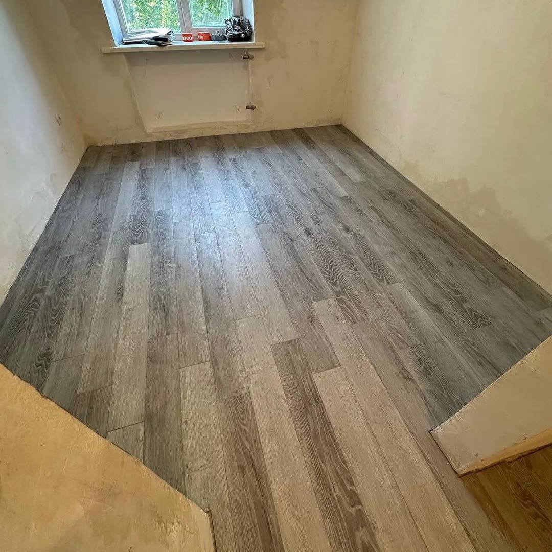 Room with new wood-effect flooring laid wall to wall, walls prepared for decorating