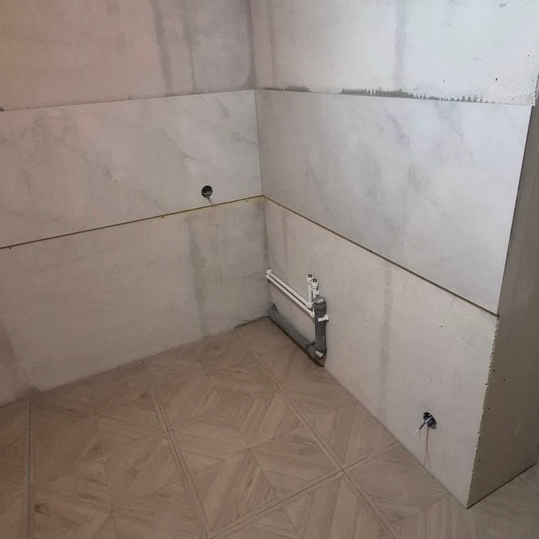 Kitchen corner with freshly skimmed walls and a newly tiled floor, services left proud of the wall