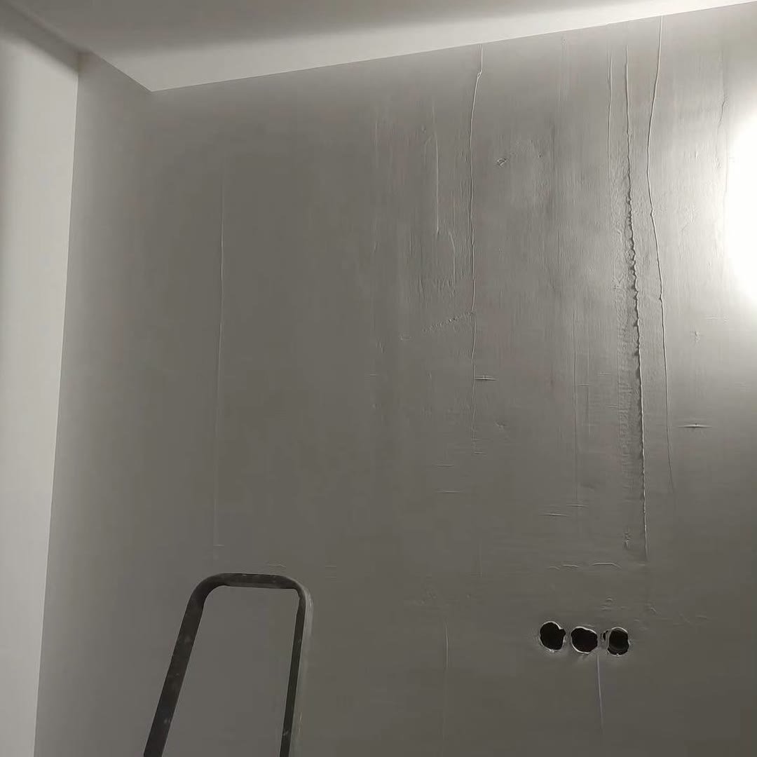 The same wall skimmed flat and smooth, the three socket holes still low on the right